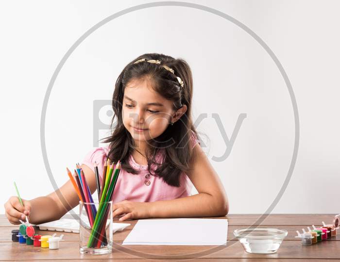 Cute little girl drawing with pencils and colours