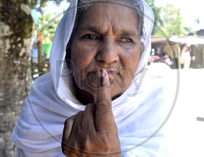 An elderly woman shows her finger marked with indelible ink
