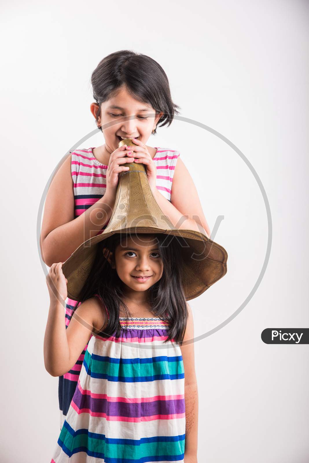 Image of small indian girls shouting / yelling in an vintage brass  gramophone speaker, isolated over white background-UU445806-Picxy
