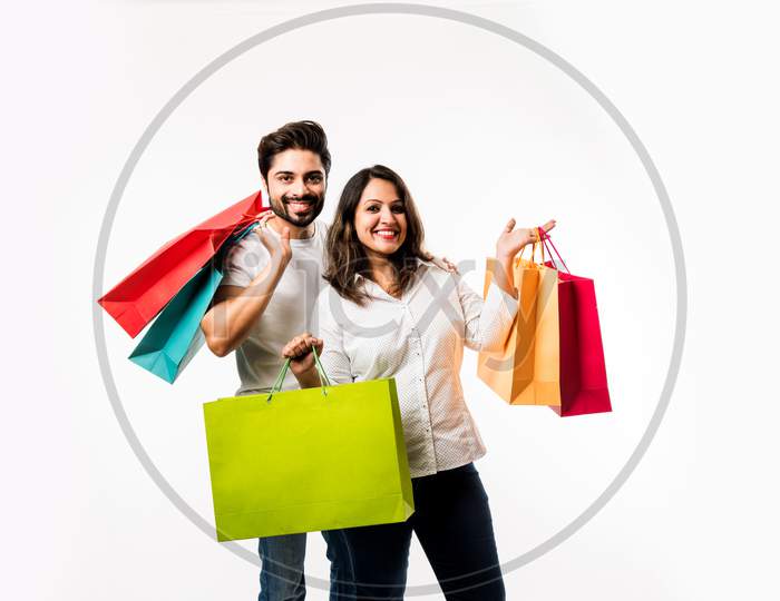 Indian young couple shopping bags and locating store, standing isolated over white bac