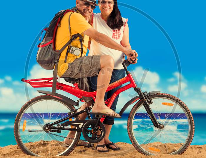 senior couple riding bicycle at beach