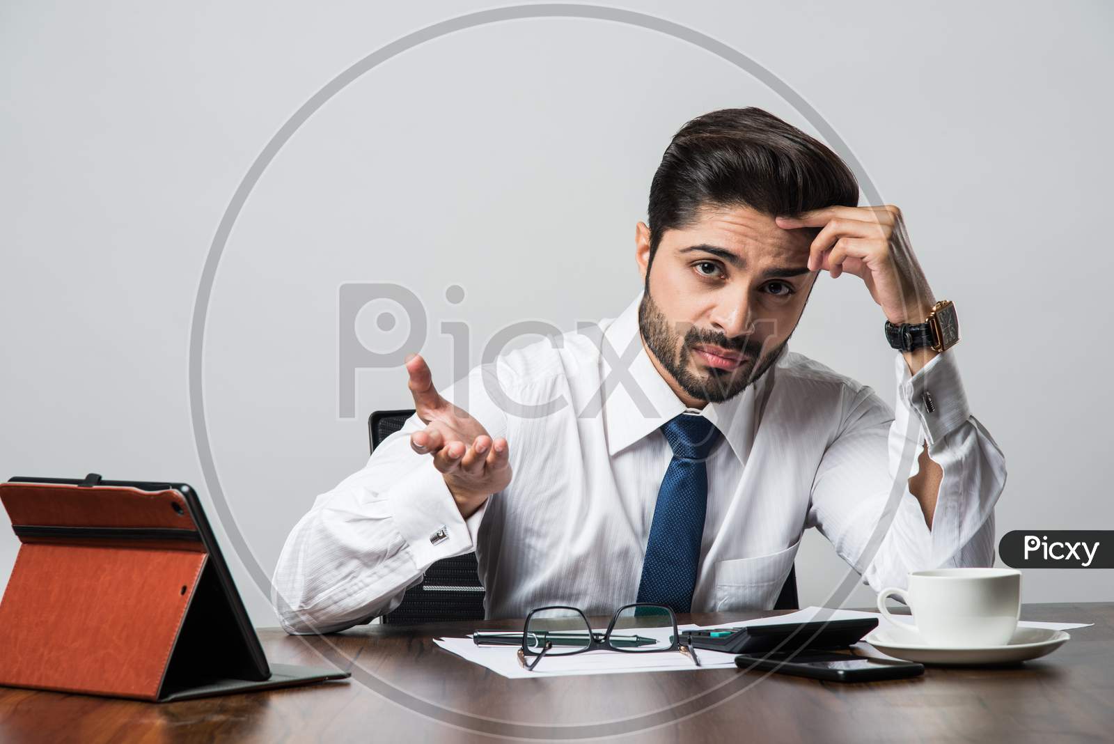 Bearded Indian Businessman accounting while sitting at desk / table in office