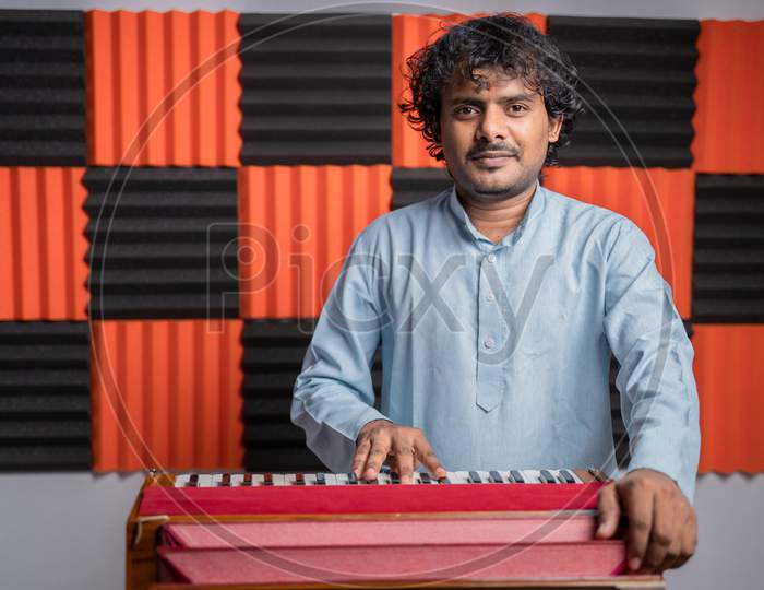 Young Musician Playing Indian Music Instrument Harmonium In Studio.