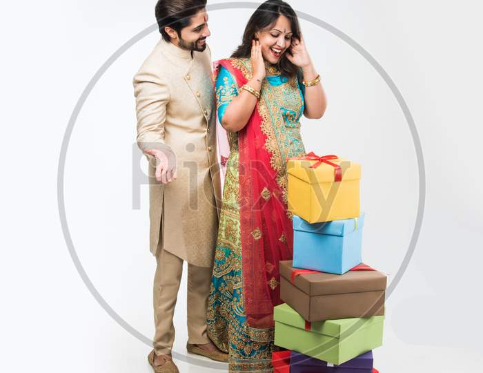 Indian Man giving surprise gift to wife, standing isolated over white background
