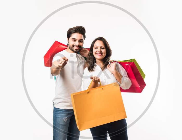Indian young couple shopping bags and locating store, standing isolated over white bac