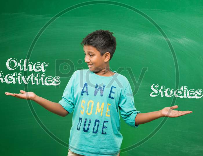 Little school boy standing in front of green scalk board with doodles - education and kids concept