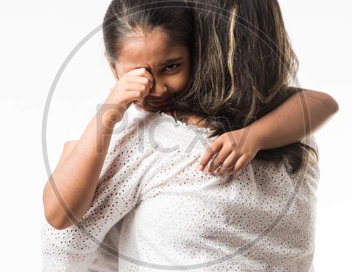 Indian girl crying in mother's arms over white background