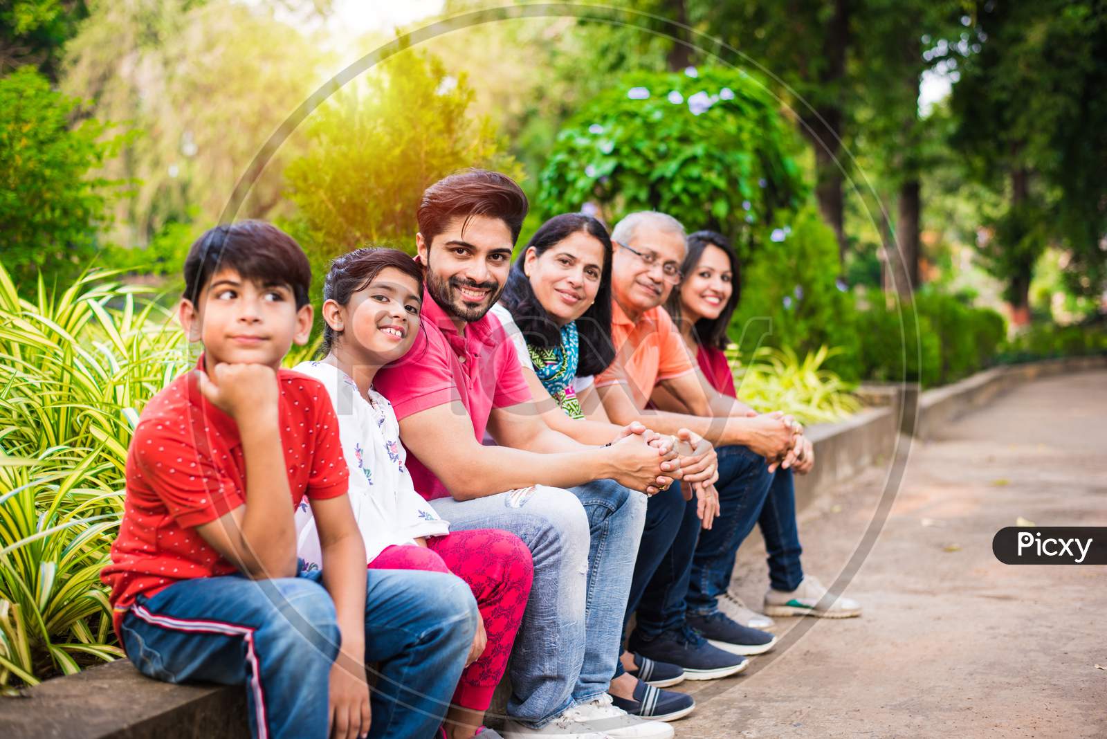 indian family of 6 sitting at wall in garden / park
