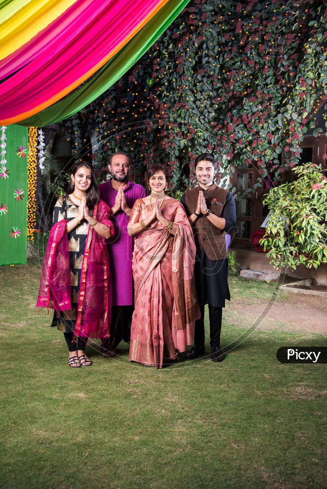 Family welcoming guests or in namaste / namaskara pose while looking at camera in celebration mood