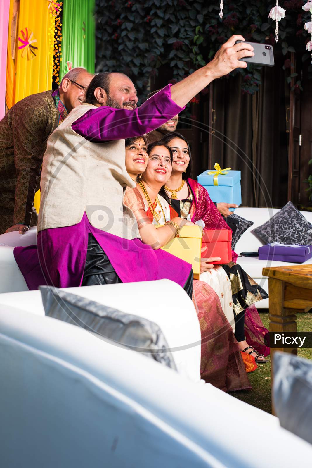 Indian family taking selfie picture using smartphone while wearing traditional festival cloths on diwali/wedding ceremony and si