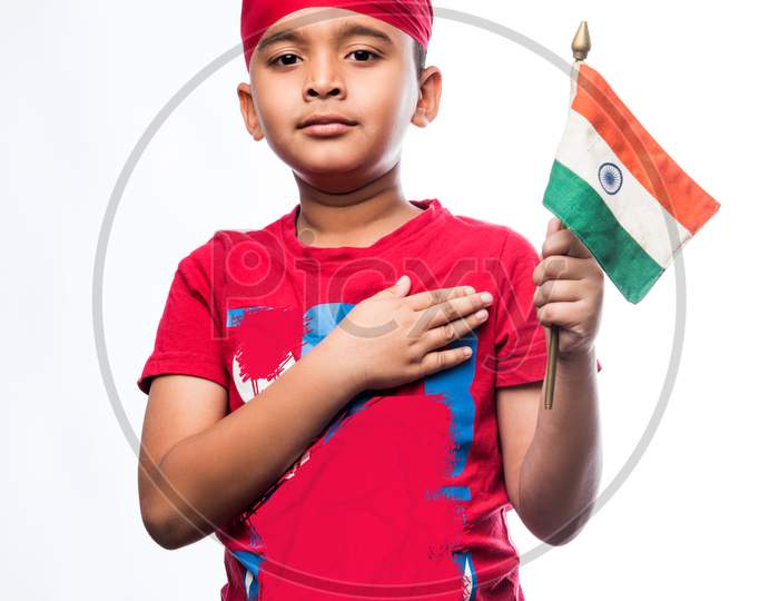 Indian sikh/punjabi little boy holding National Tricolour flag while standing isolated over white background