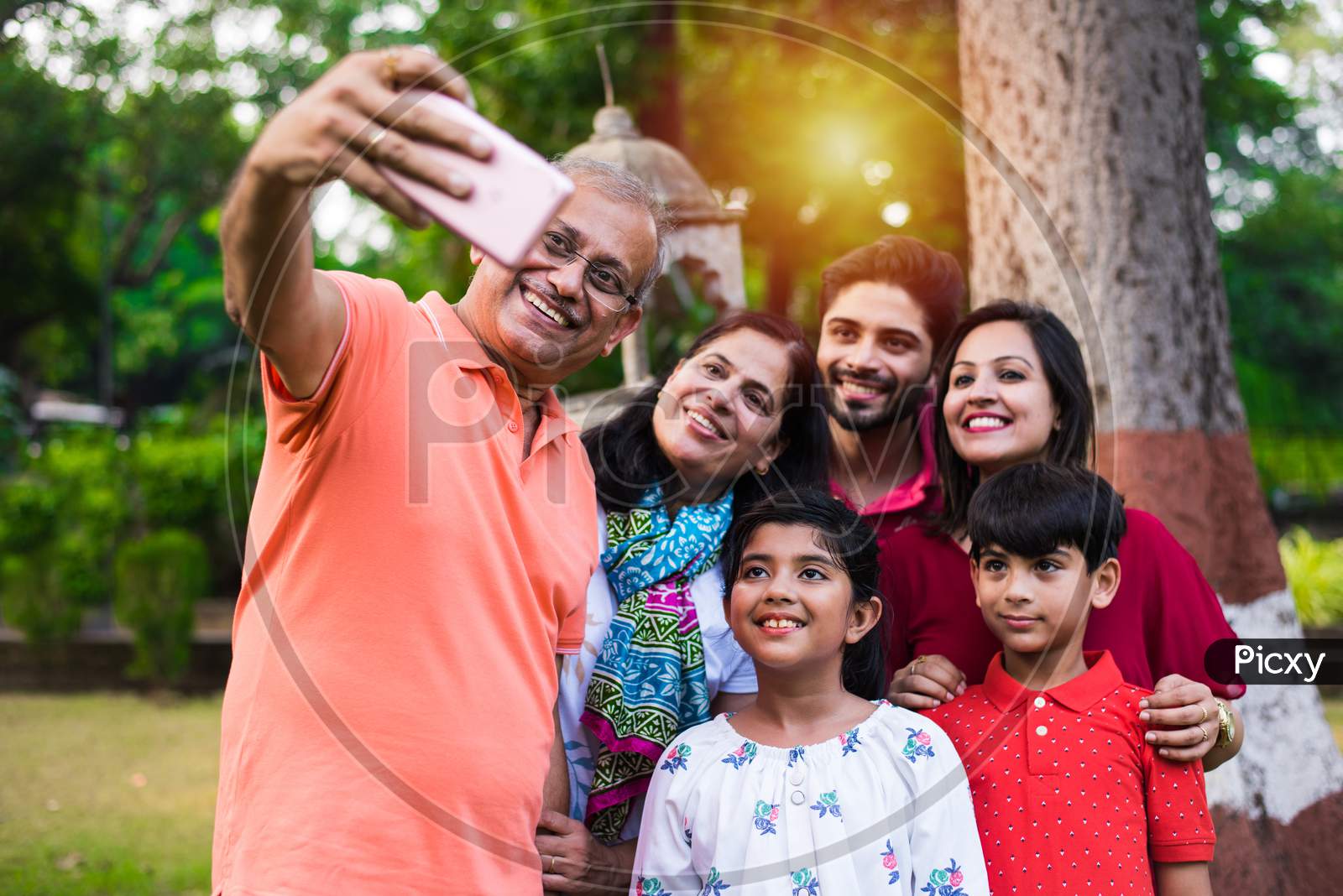 indian grandfather taking selfie picture of his family includes his wife, son, daughter in law and grand children