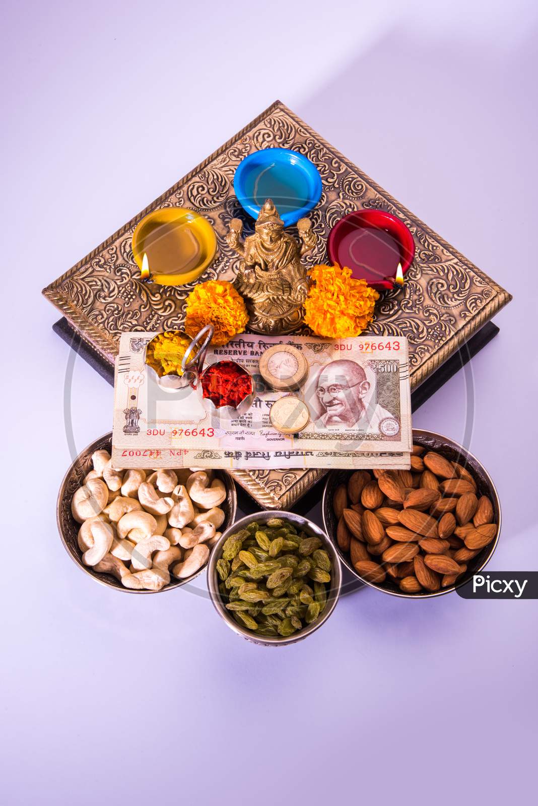 Laxmi Puja with dry fruits, Indian rupees, diya and flower