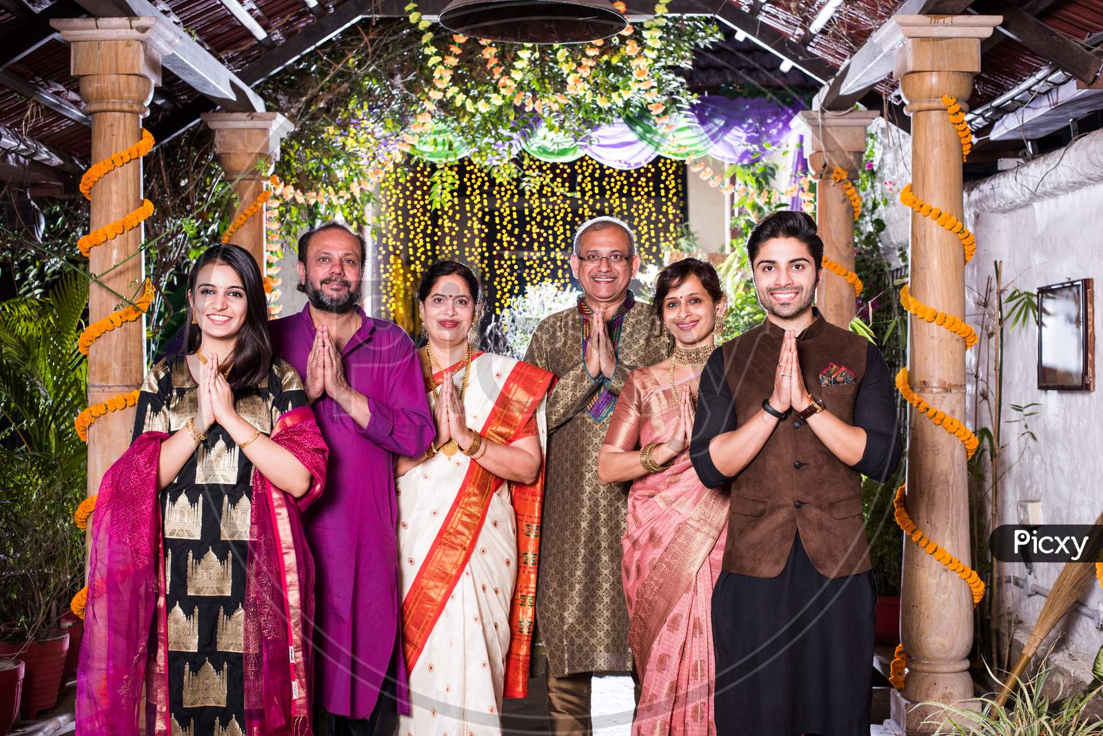 Family welcoming guests or in namaste / namaskara pose while looking at camera in celebration mood