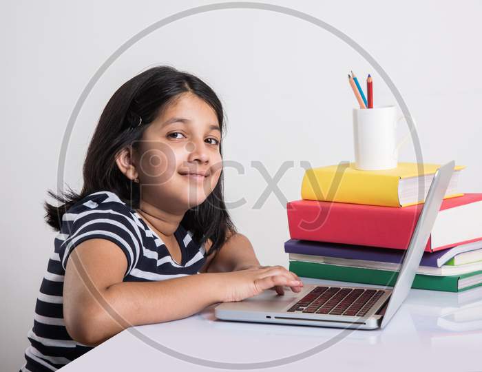 Indian school girl studying with laptop and books