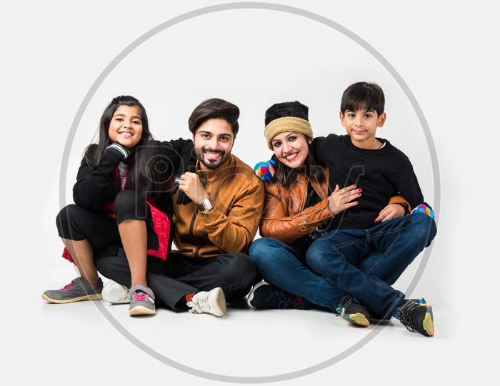 Indian family in warm clothes sitting against white background. Ready for winter