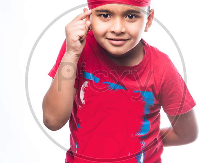 Portrait of Indian Sikh/punjabi little boy thinking while standing isolated over white background