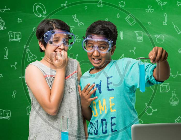 small boy and girl studying science in classroom against green chalkboard background with science doodles