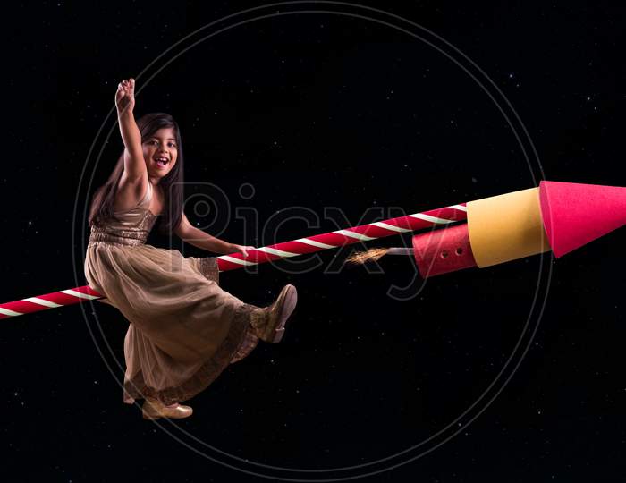 Concept showing cute indian girl riding on Diwali Rocket and travelling to space