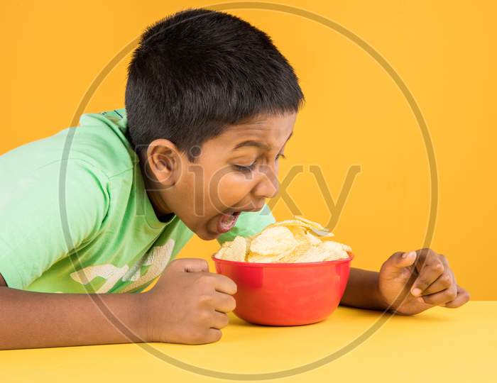Cute little boy eating potato wafers or crispy chips