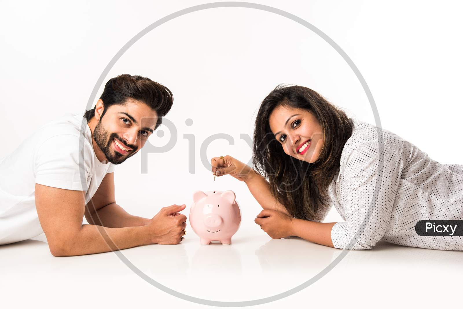 Indian couple with piggy bank, isolated over white background