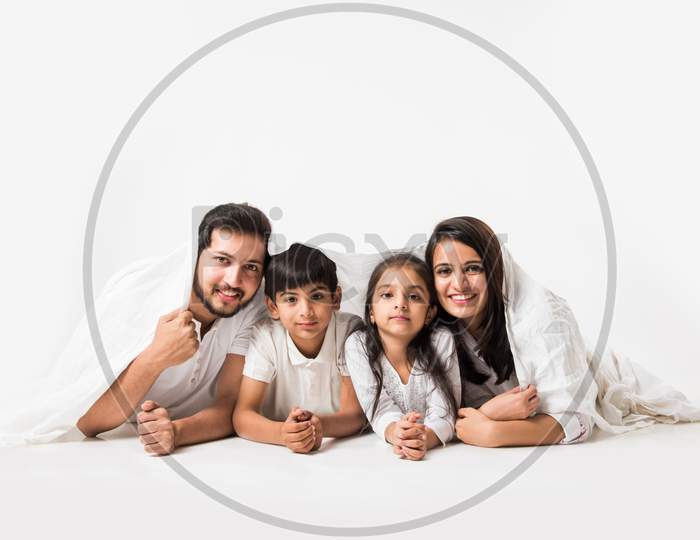 Indian parents with children lying under bed cover