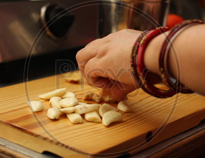 Woman Cutting Garlic On Chopping Board