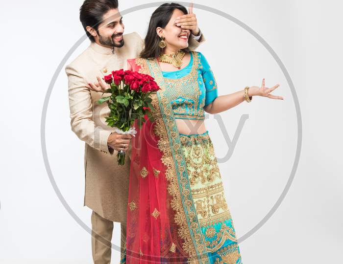 Indian Man giving rose flowers bouquet to wife, standing isolated over white background