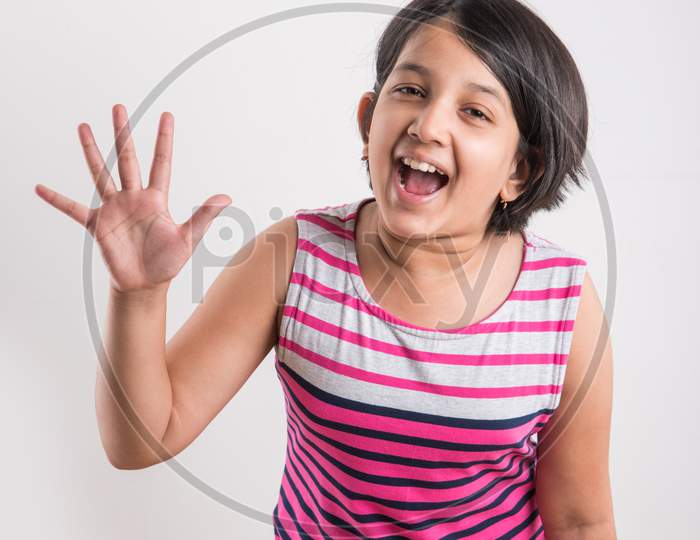 Indian small girl showing numbers with fingers over white background