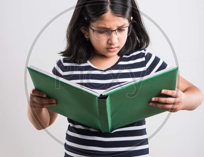 Indian school girl studying with book while standing