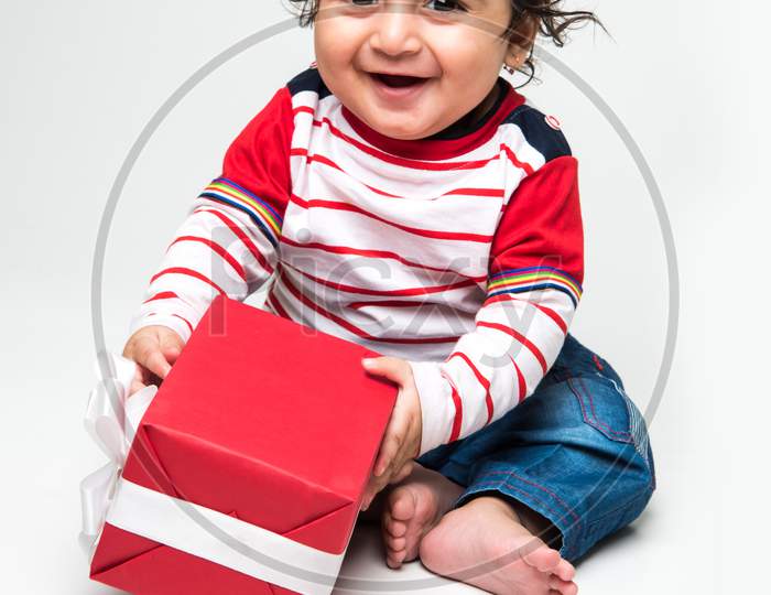 Indian cute little baby /infant or toddler smiling with gift box over white background