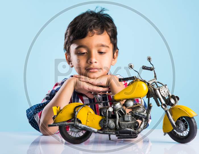 cute little kid mechanic trying to fit toy motor bike