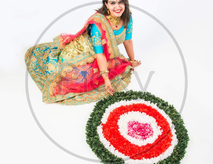 girl/woman making flower rangoli for hindu festival celebration, sitting over white background, selective focus