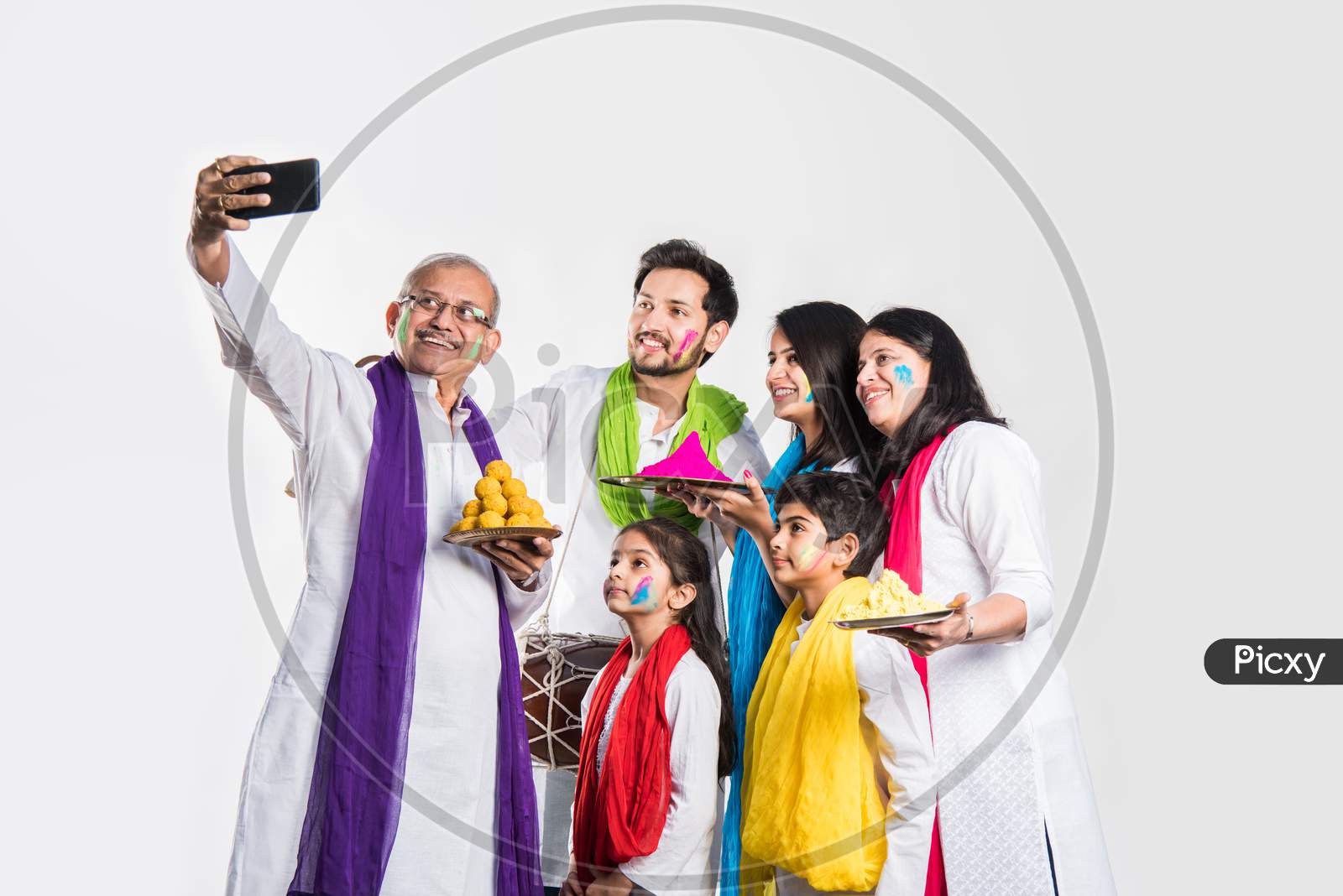 Indian Family taking selfie picture on Holi festival while holding sweets and colours