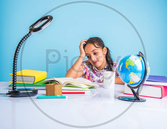 Indian school girl studying at home with books