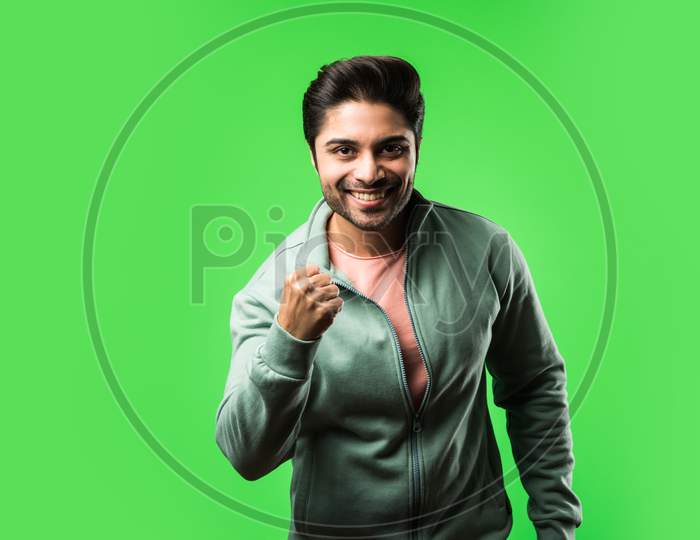 Indian handsome man with success gesture, standing isolated over green background