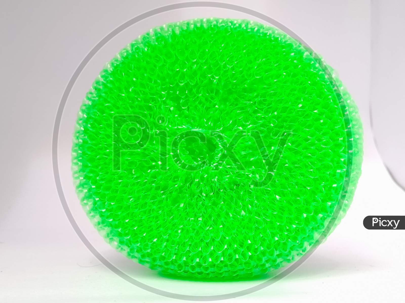 A Closeup Shot Of A Green Plastic Scrubber Placed Isolated Vertically On A White Background.