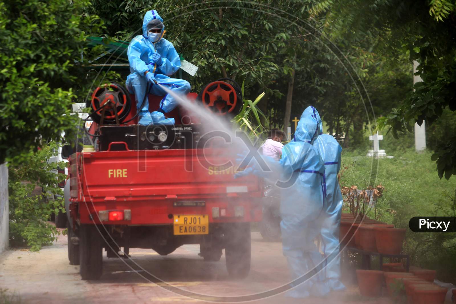 A municipal worker sprays disinfectant on his colleague after they cremated a person who died of coronavirus infection in Ajmer, Rajasthan on July 12, 2020