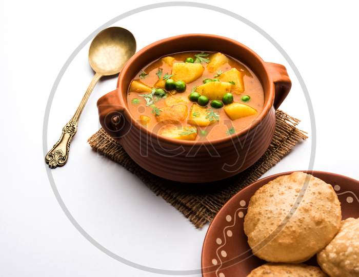 Aloo Curry Sabzi made using boiled potato with green peas. Served in a bowl or karahi, selective focus