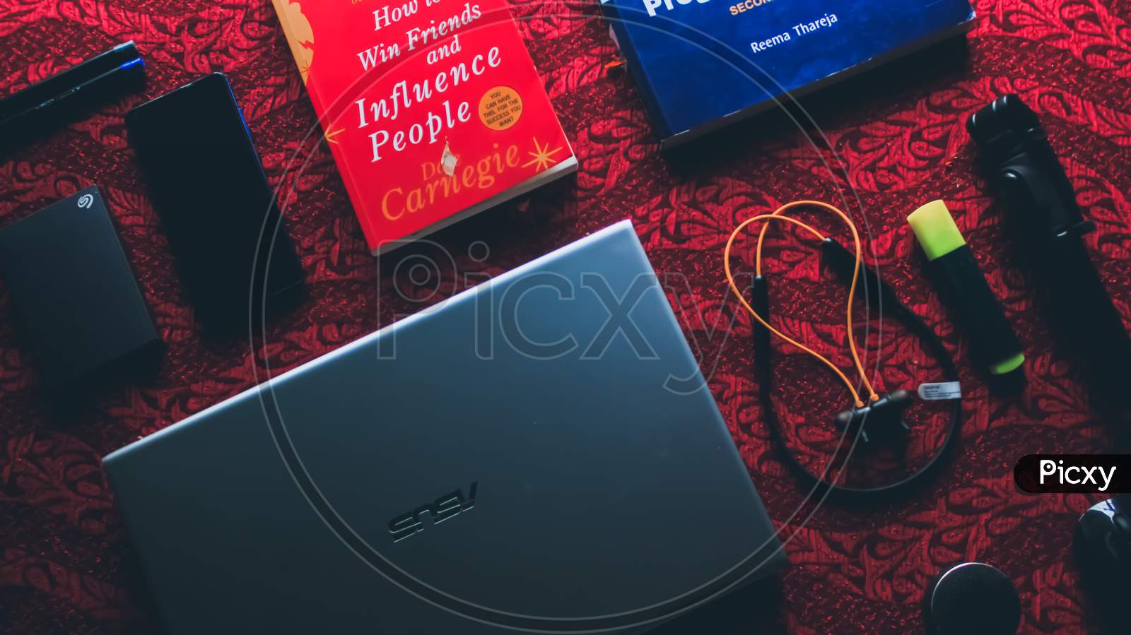 Portable electronics and books on the cleared red table.
