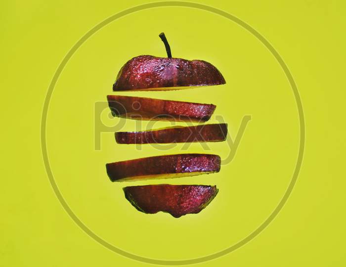 Apple pieces are floating in the air in front of a yellow background.