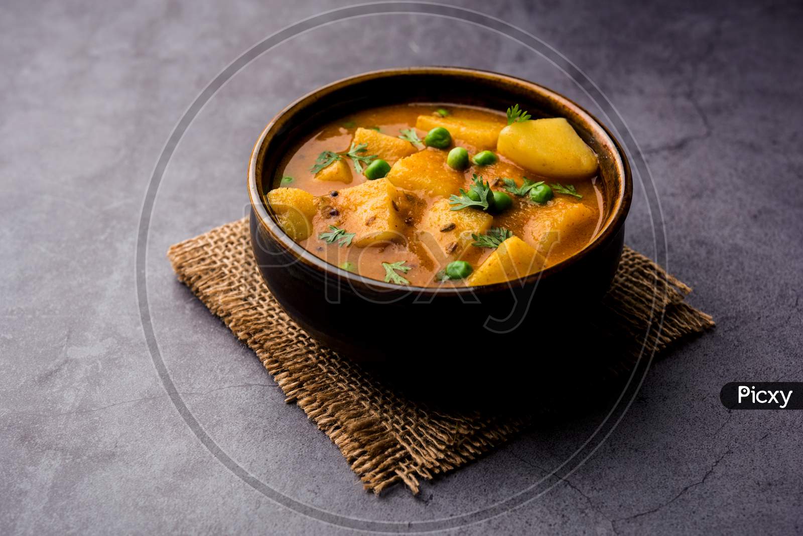 Aloo Curry Sabzi made using boiled potato with green peas. Served in a bowl or karahi, selective focus