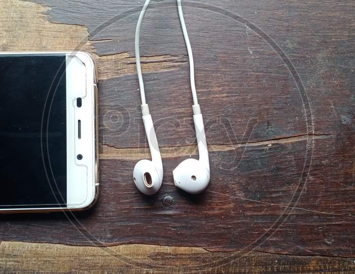 Smartphone and earphone in wooden table