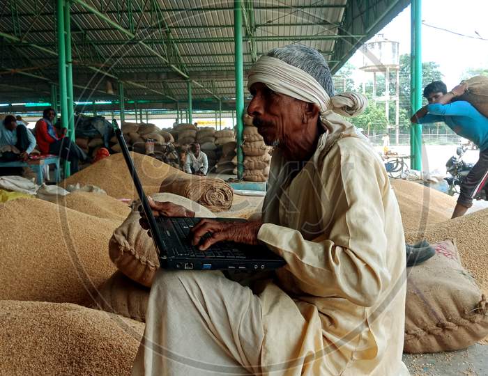 an indian village man operating laptop at farmers place on 2019 in India
