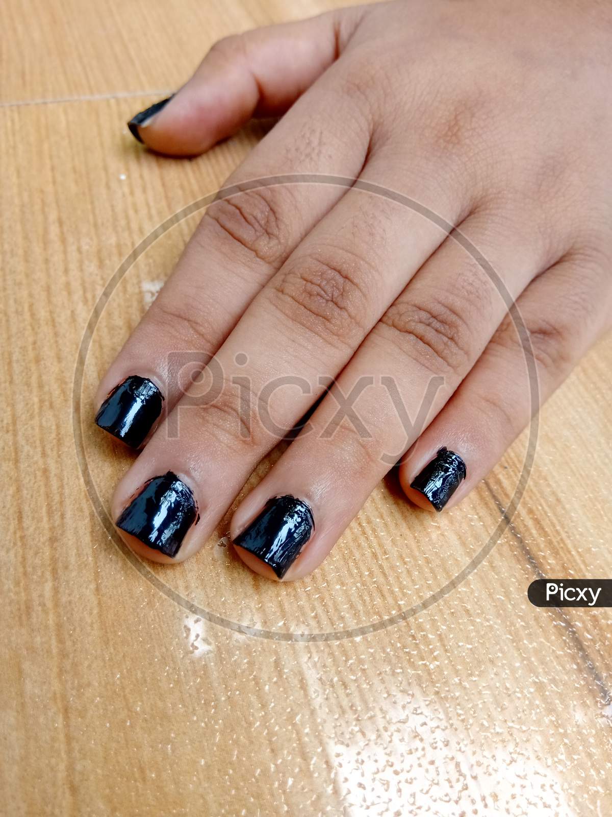 A Black Nail Polished Hand On Table