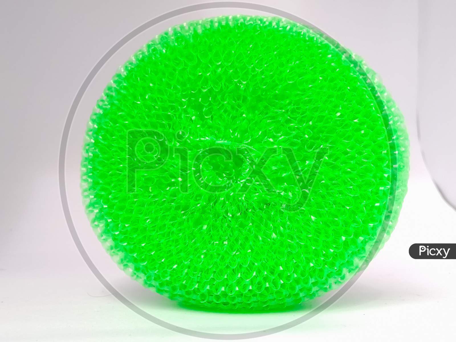 A Closeup Shot Of Green Plastic Scrubber Placed Isolated Vertically On A White Background.