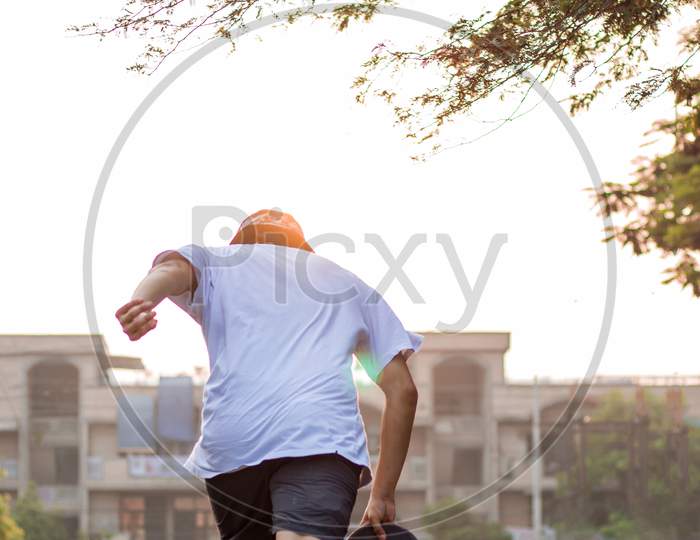 A Young Adult Charging Forward With His Skateboard On An Empty Street During Sunrise.