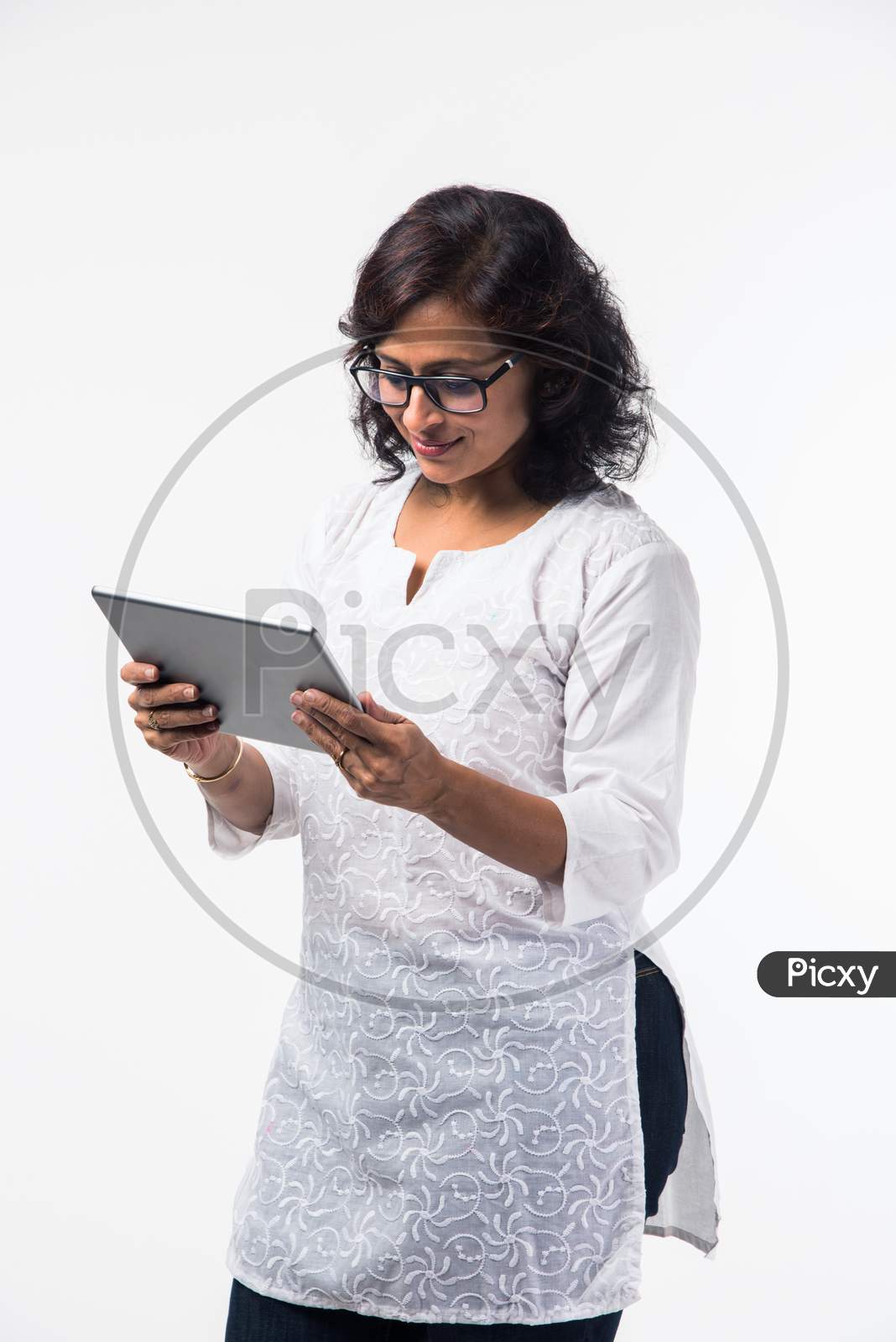indian lady/women using tablet pc while standing isolated over white background, selective focus