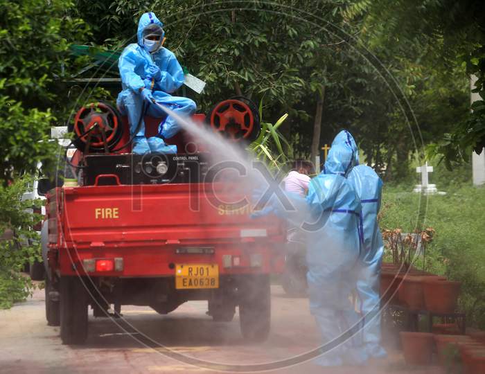 A municipal worker sprays disinfectant on his colleague after they cremated a person who died of coronavirus infection in Ajmer, Rajasthan on July 12, 2020