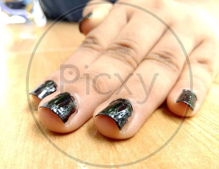 A Soft Beautiful Palm With Black Nail Polish Placed On A Table Top.